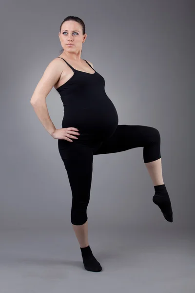 灰色の背景に体操をやっている妊娠中の女性. — ストック写真