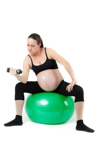 Schöne schwangere Frau sitzt mit Übung bal. isoliert auf — Stockfoto