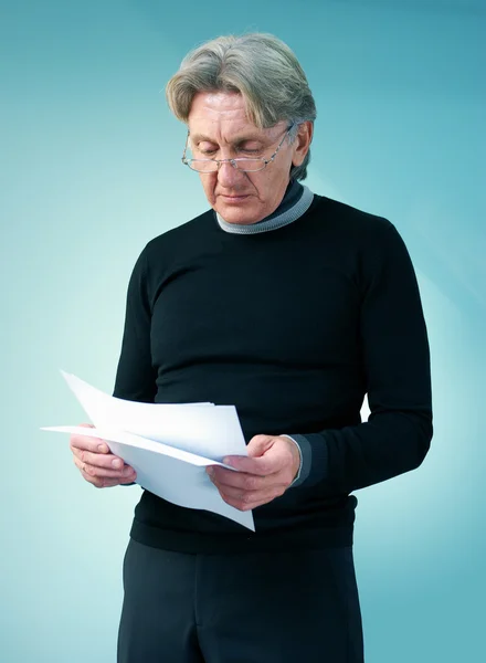 stock image Senior man reading important papers. Attractive seniors lifestyle in studio uniform background series.