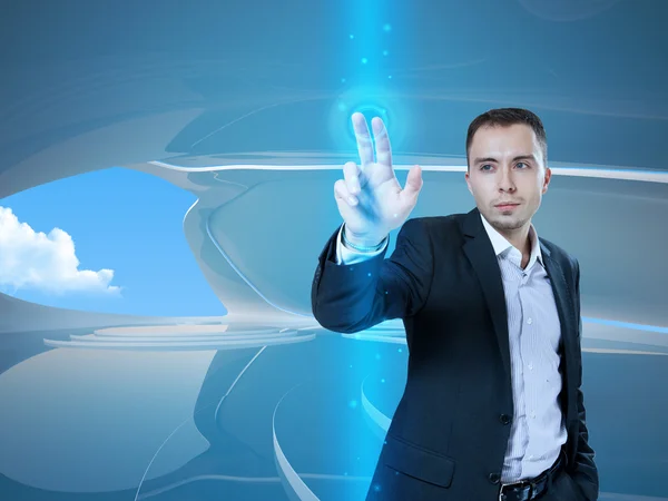 Jeune homme d'affaires élégant touchant bouton d'interface virtuelle. Pilier de lumière bleue transparente. Futur intérieur de style bio sur fond. Collection d'interfaces — Photo
