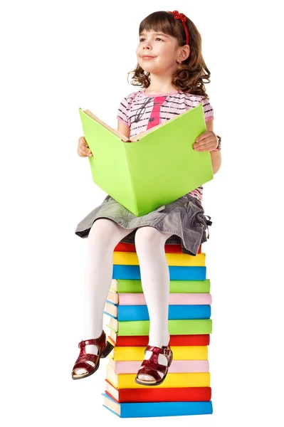 Kitap yığını üzerinde oturan küçük kız — Stok fotoğraf