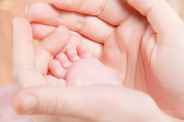 女性の手で赤ちゃんの足 — ストック写真