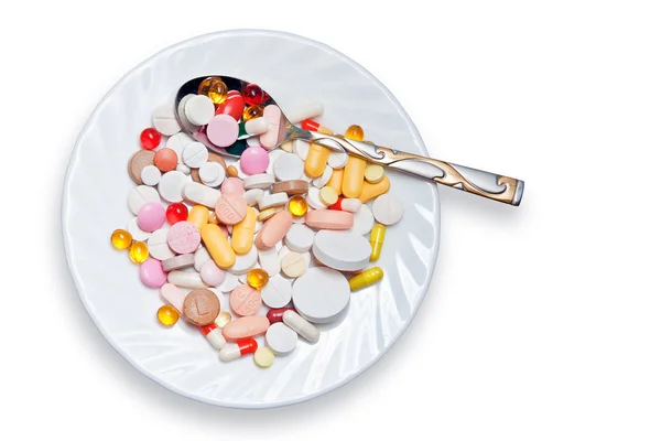 Spousta barevných pilulek na talíř a lžíci — Stock fotografie