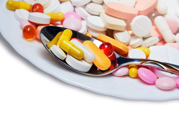Mnóstwo kolorowych tabletek na płytkę i łyżka — Zdjęcie stockowe