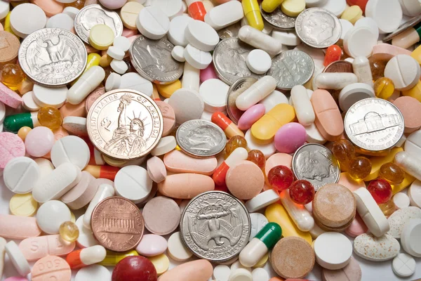 Wiele tabletek z monet wśród nich — Zdjęcie stockowe