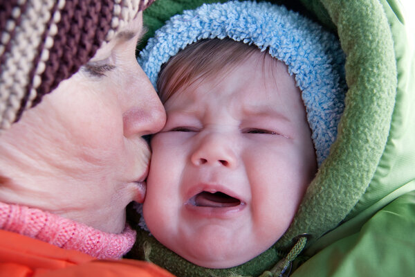Бабушка целует плачущего ребенка
.