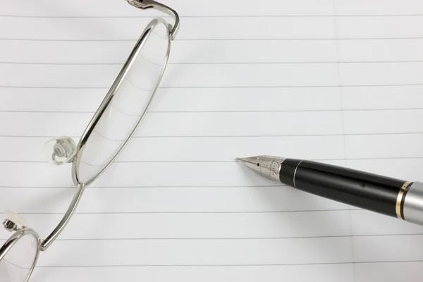 Caneta-tinteiro, bloco de notas e óculos — Fotografia de Stock