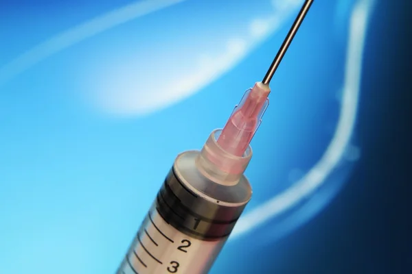 Syringe against blue background — Stock Photo, Image