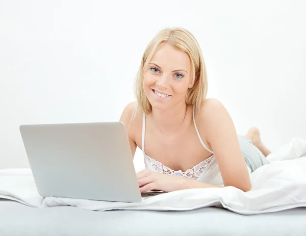 Young beautiful woman using laptop in bed — Stock Photo, Image