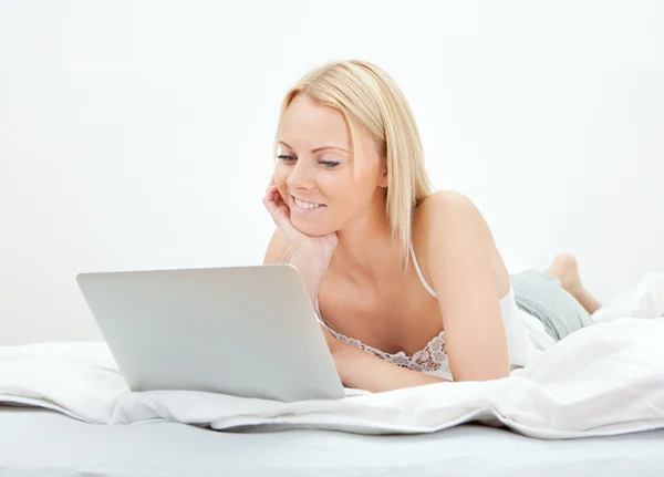 침대에서 노트북을 사용 하 여 젊은 아름 다운 여자 — 스톡 사진