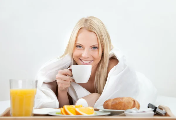 Schöne Frau trinkt Kaffee im Bett — Stockfoto