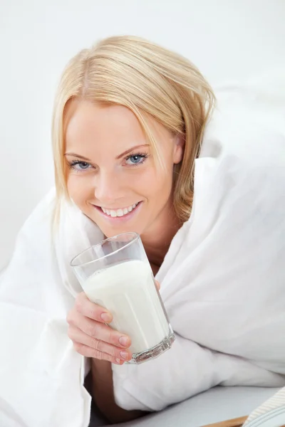 Beautiful woman drinking milk in bed — Stock Photo, Image