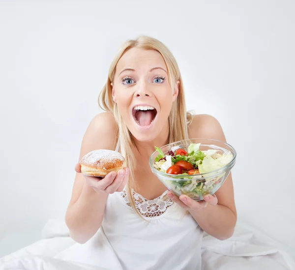 Tempted young woman making a food choice — Stock Photo, Image