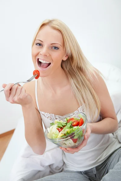 Schöne Frau isst grünen Salat Stockbild