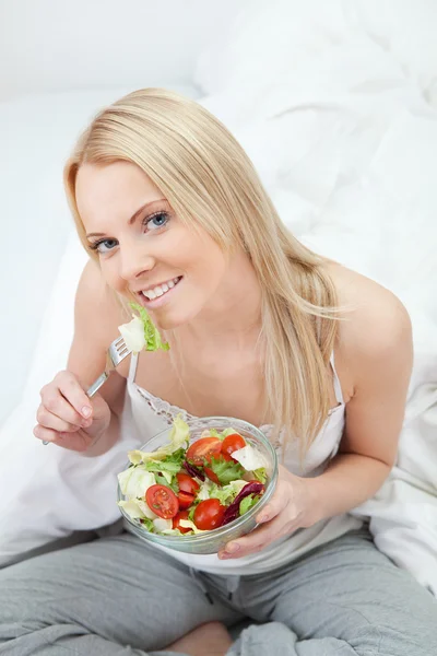 Schöne Frau isst grünen Salat lizenzfreie Stockbilder