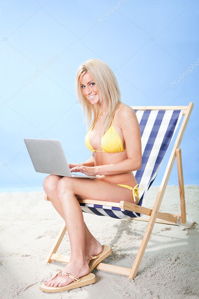 Young woman in bikini using laptop