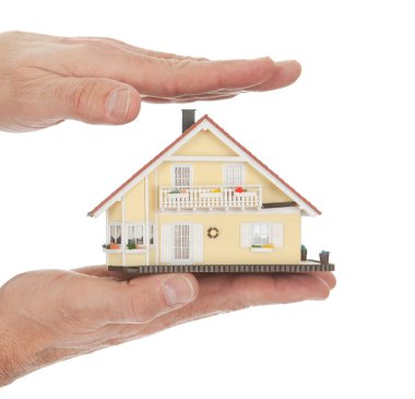 Businessman holding model of a house in hands clipart