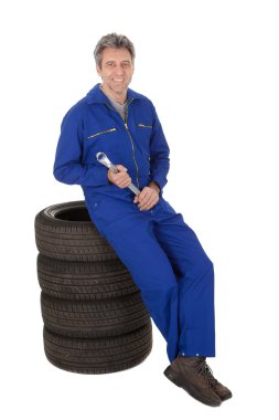 Automechanic sitting on car tires clipart