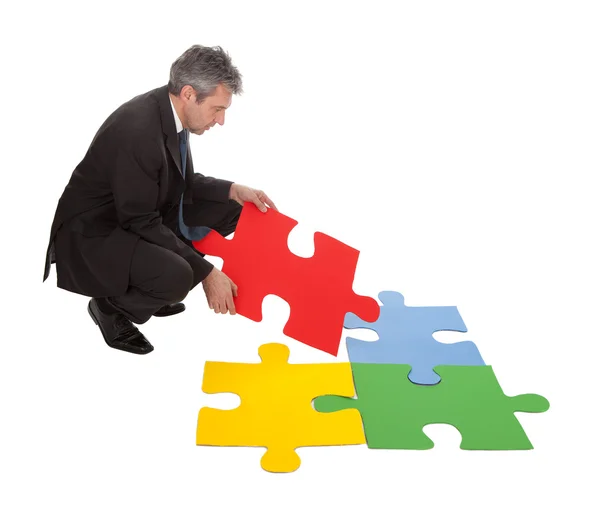 Homme d'affaires senior assemblant un puzzle — Photo