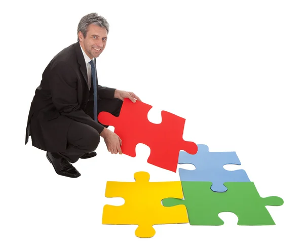 Senior businessman assembling a jigsaw puzzle — Stock Photo, Image