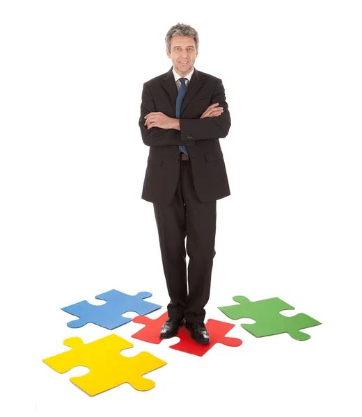 Senior businessman standing on a jigsaw puzzle — Stock Photo, Image