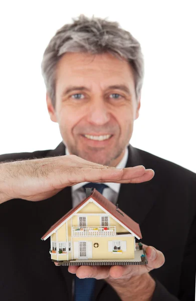 Бизнесмен держит в руках модель дома — стоковое фото