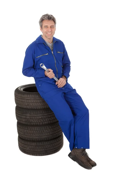 Automechanic siedzi na opony samochodowe — Zdjęcie stockowe