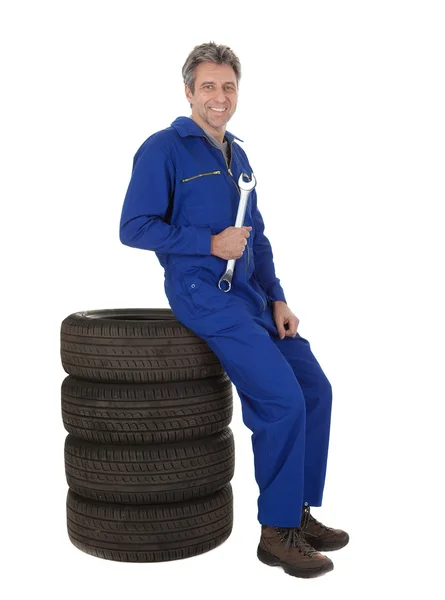 Automecânico sentado em pneus de carro — Fotografia de Stock