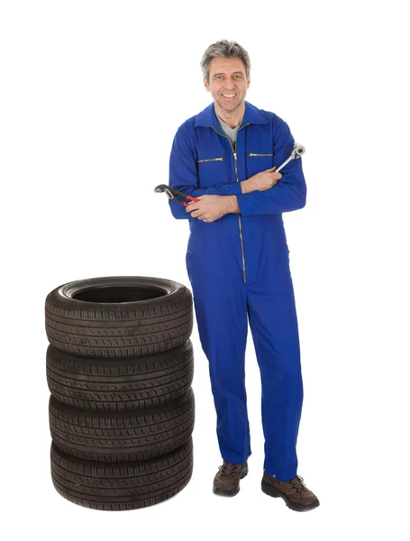 Automecánico de pie junto a los neumáticos del coche —  Fotos de Stock