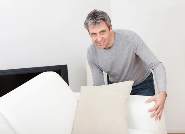 Senior man moving sofa — Stock Photo, Image