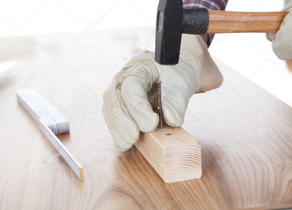 Worker hammering a nail into piece of wood