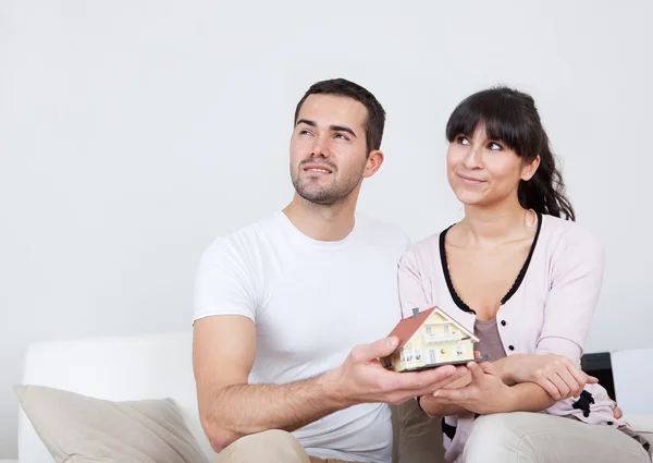Happy young couple holding a house model — Stock Photo, Image
