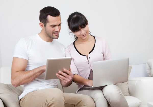 年轻的夫妇在沙发上使用笔记本电脑 — 图库照片