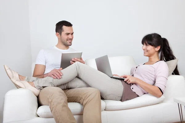 Ungt par med bärbara datorer i soffan — Stockfoto