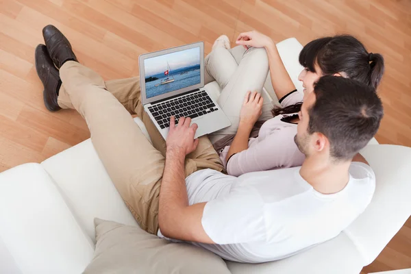 Młoda para korzysta z laptopa w kanapie — Zdjęcie stockowe