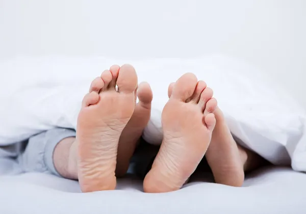 Ноги пары под одеялом — стоковое фото
