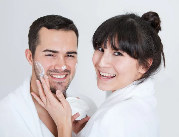 Playful young couple applying cream — Stock Photo, Image