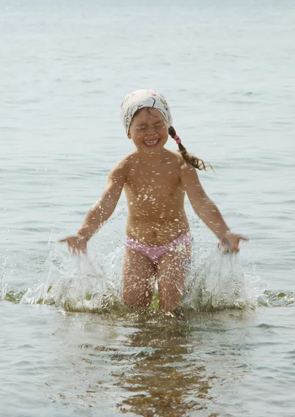 The happy girl plays the sea — Stock Photo, Image