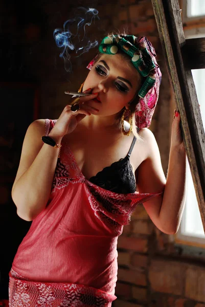 Smoking pin up girl on the attic in lingerie with curlers — Stock Photo, Image