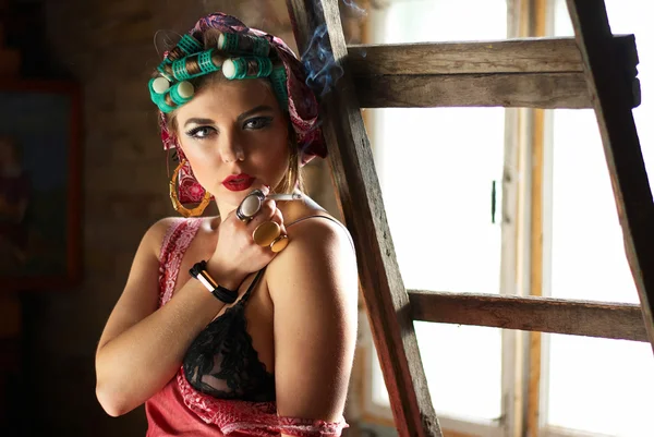 Smoking pin up girl on the attic in lingerie with curlers — Stock Photo, Image