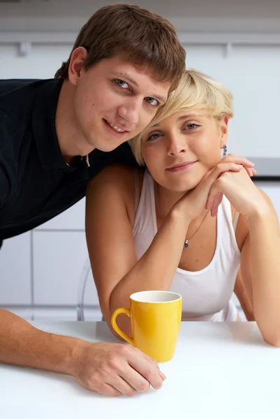 Happy couple posing in the kitchen with cups — Stock Photo, Image