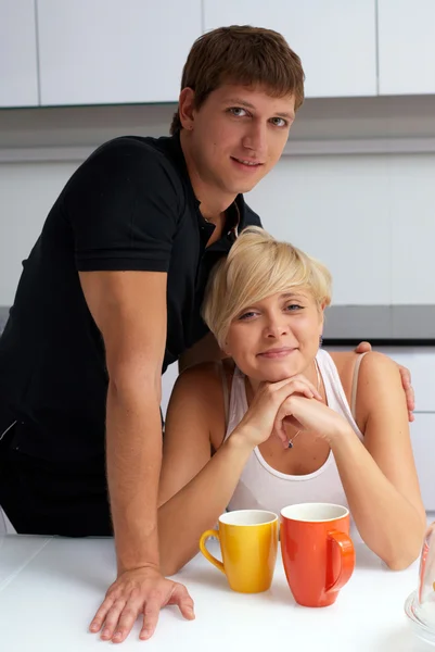 Happy couple posing in the kitchen with cups — Stock Photo, Image