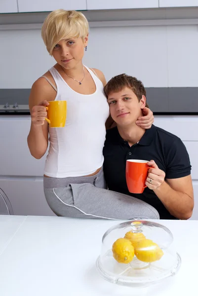 Szczęśliwa para pozowanie w kuchni z filiżanki i cytryny — Zdjęcie stockowe