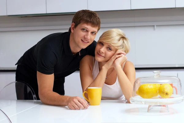 Happy couple posing in the kitchen with cups and lemons — Stock Photo, Image