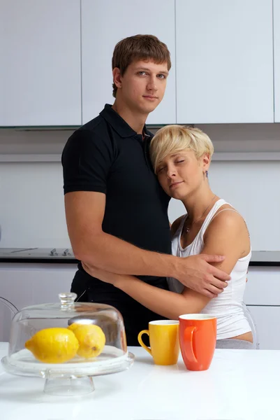 Couple heureux posant dans la cuisine avec des tasses et des citrons — Photo