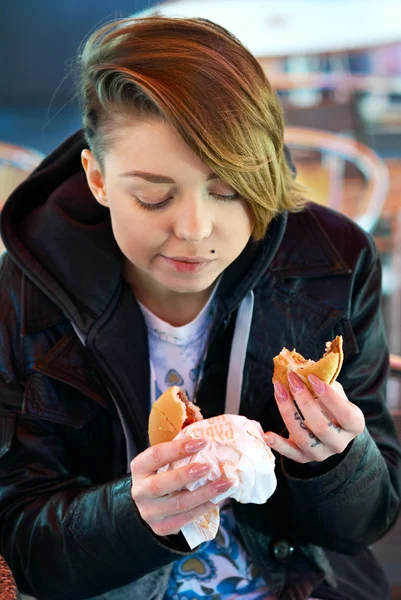 Portret van meisje met eet Hamburger op het terras van de snelle foo — Stockfoto