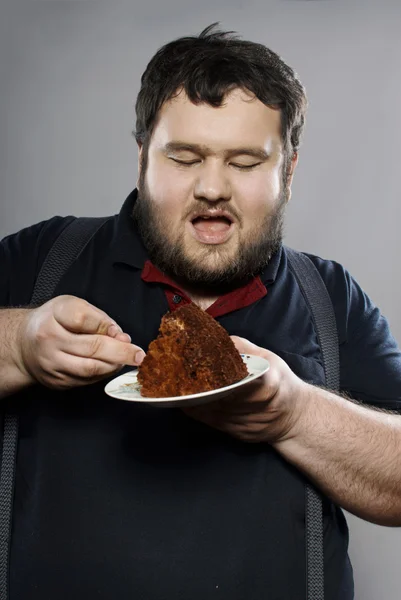 초콜릿 케이크를 먹는 재미 있는 뚱뚱한 남자 — 스톡 사진