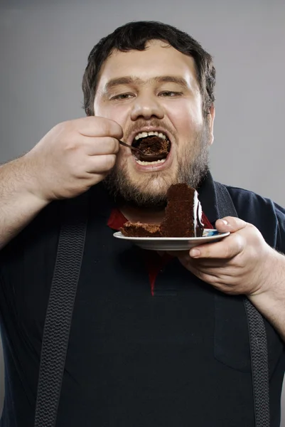 Lustiger fetter Kerl, der Schokoladenkuchen isst — Stockfoto