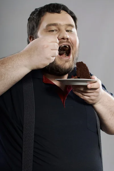 초콜릿 케이크를 먹는 재미 있는 뚱뚱한 남자 — 스톡 사진