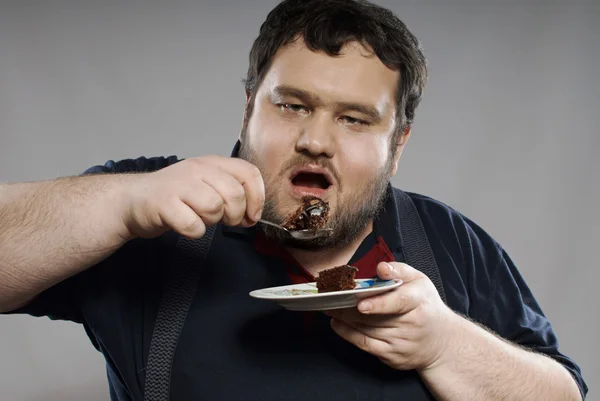 Divertente ragazzo grasso mangiare torta al cioccolato Fotografia Stock